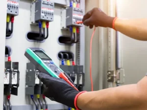 Technicien réalisant un diagnostic et une mesure électrique sur un tableau pour une formation dépannage industriel